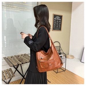 Detail of soft brown leather crossbody bag with multiple silver zippers in coffee shop