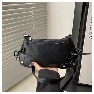 Detail view of black crescent handbag with leather bows and silver rivets on the side