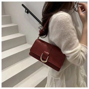 Détail du sac à bandoulière en cuir gaufré bordeaux avec boucle fer à cheval dorée