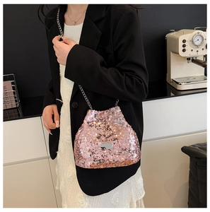 Pink sequin bucket bag with silver chain strap worn by model in a stylish setting