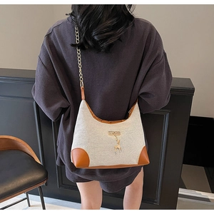 Gros plan d'un sac bandoulière en toile avec finitions cuir et chaîne dorée sur mannequin