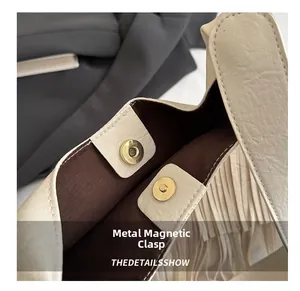 Detailed macro view of golden magnetic clasps on a white pebbled leather tote bag