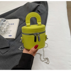 Detail of lime green leather bucket bag showing dual silver zippers and chain strap
