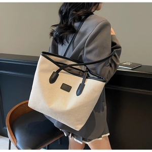 Detail of contrast stitch tote bag featuring dual handles and textured canvas finish
