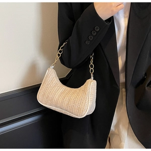 Detail of woven straw baguette bag with metal chain strap and herringbone texture