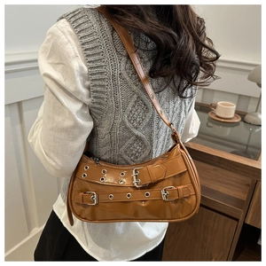 Detailed view of caramel brown motorcycle style shoulder bag with silver belt buckles