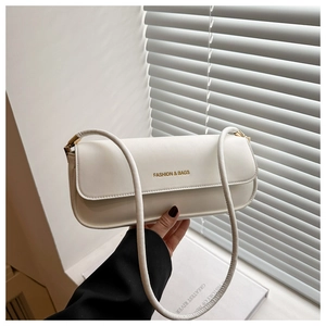 Detailed close-up of white rectangular shoulder bag featuring gold fashion typography