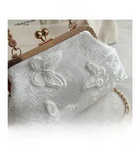 Close-up of white lace embroidery evening bag featuring 3D butterfly appliques and gold clasp