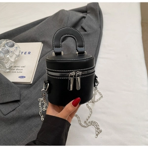Close-up of black leather bucket bag featuring white contrast stitching and chain strap