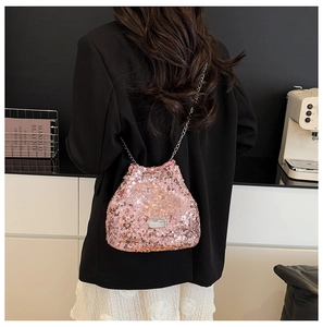 Pink sequin bucket bag with silver chain strap shown in a modern lifestyle setting