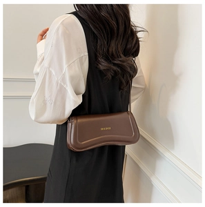 Brown faux leather shoulder bag with unique wavy bottom design shown on a model
