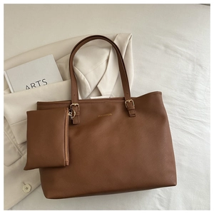 Gros plan du sac cabas en cuir marron à motif croisé avec boucle en métal doré et détail