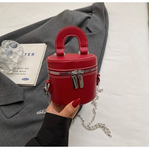 Close-up of red cylindrical mini bag with white stitching and silver chain strap