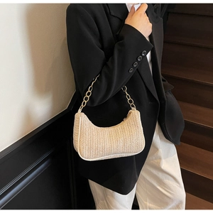 Detail of woven straw shoulder bag with gold chain strap in a stylish summer look