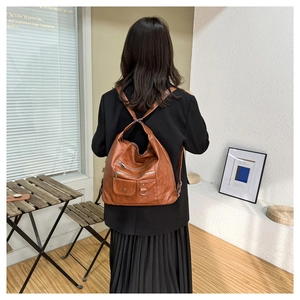 Lifestyle shot showing a brown vintage soft leather backpack with multiple zip pockets