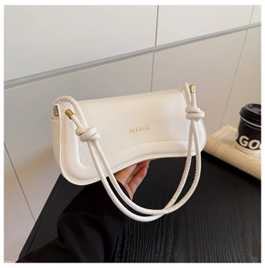 Close-up of white leather handbag featuring knotted rope strap and golden metal hardware