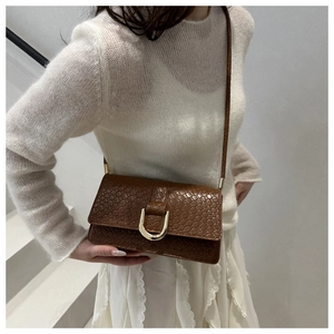 Detail of vintage brown crocodile textured handbag with golden horseshoe buckle
