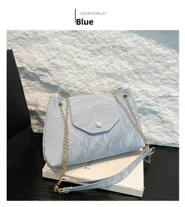Detail der blauen Schultertasche mit Textur und goldener Kette auf Felsenhintergrund