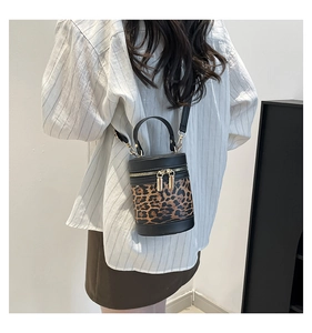 Detail of leopard print cylinder bag with black leather trim and golden zippers