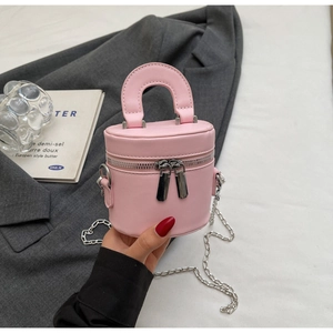 Detail view of a pink cylinder vanity bag with silver chain strap and matte leather