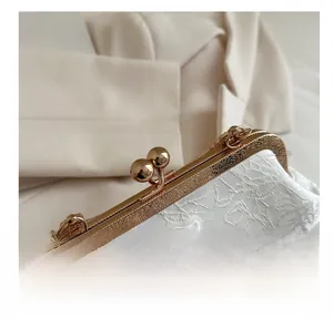 Detailed close-up of a white lace handbag featuring antique gold engraved metal clasp