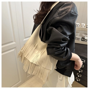 Detail of cream tassel crossbody bag showing long fringe texture on leather surface