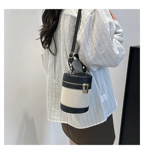 Linen bucket bag with black leather trim and gold zippers worn by model on shoulder