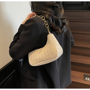 Detail of woven straw baguette bag with elegant gold chain strap texture