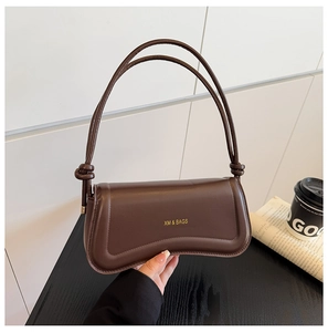 Detail of dark brown retro shoulder bag showing smooth texture and golden logo