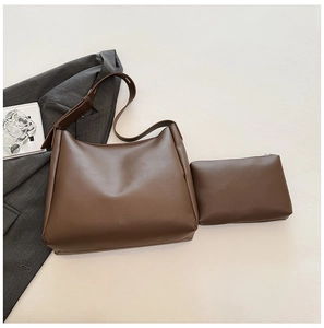Flat lay of brown faux leather tote bag and matching pouch on grey blazer background