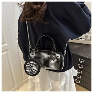 Detail view of black rivet cylinder bag with matching mini round pouch on a model