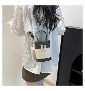 Detail of color-block linen bucket bag with dual zippers and adjustable strap shown on model