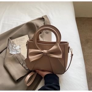 Chic beige bow handbag on bed with aesthetic lifestyle props for a trendy fashion look