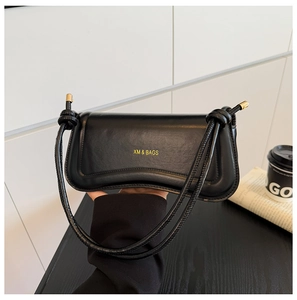 Detailed view of black vintage flap bag with wave contour and gold logo lettering