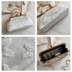 Detail view of white lace floral clutch with 3D butterfly embroidery and metal chain