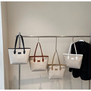Hanging display of canvas tote bags in black, brown, khaki, and white leather trims