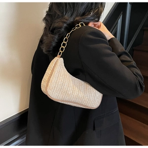 Detail of cream woven straw underarm bag with chic herringbone texture and gold chain strap