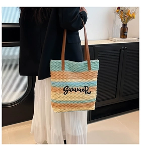 Close-up of woven straw tote bag with Summer embroidery and brown leather handles