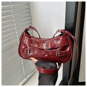 Close-up of deep red leather shoulder bag with punk buckles and metal eyelets