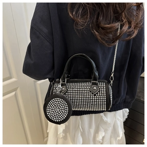 Detail of black cylinder bag with sparkling studs and chain strap worn by a model