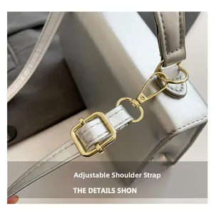 Detail of adjustable shoulder strap with gold-tone hardware on silver metallic bag