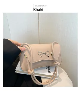 Detail of khaki faux leather shoulder bag featuring a golden metal bow buckle on the flap