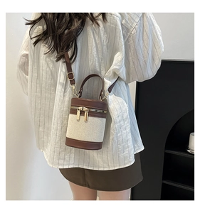 Detail of color-block cylinder bag showing canvas texture and brown leather trim