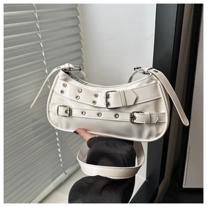 Close-up of white crescent crossbody bag with punk style silver buckles and eyelets