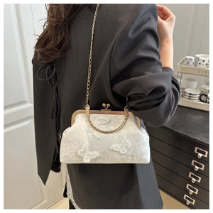 Close-up of white lace embroidery with butterfly motifs on a vintage-style chain handbag