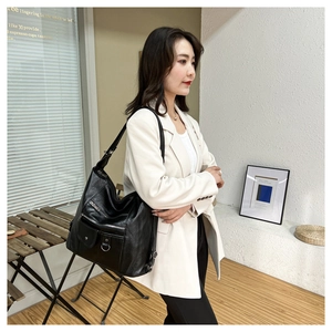 Lifestyle view of a black multi-pocket leather tote bag worn on shoulder in a modern setting