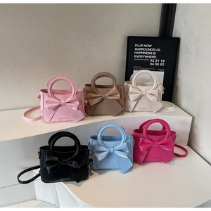 Chic small square bags with oversized bow detail in multiple colors on a tiered display