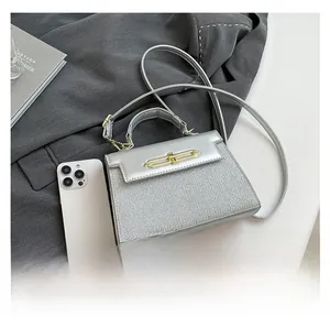 Silver glitter crossbody bag with gold lock shown next to a smartphone for size reference