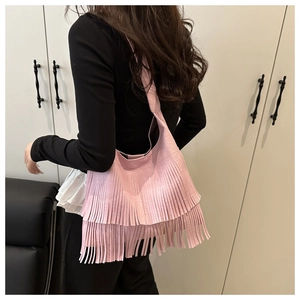 Detail view of pink crossbody bag featuring long flowing tassels in a bohemian style