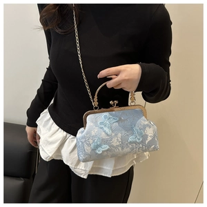 Détail d'une pochette de soirée en dentelle bleu clair avec papillons 3D et anse dorée